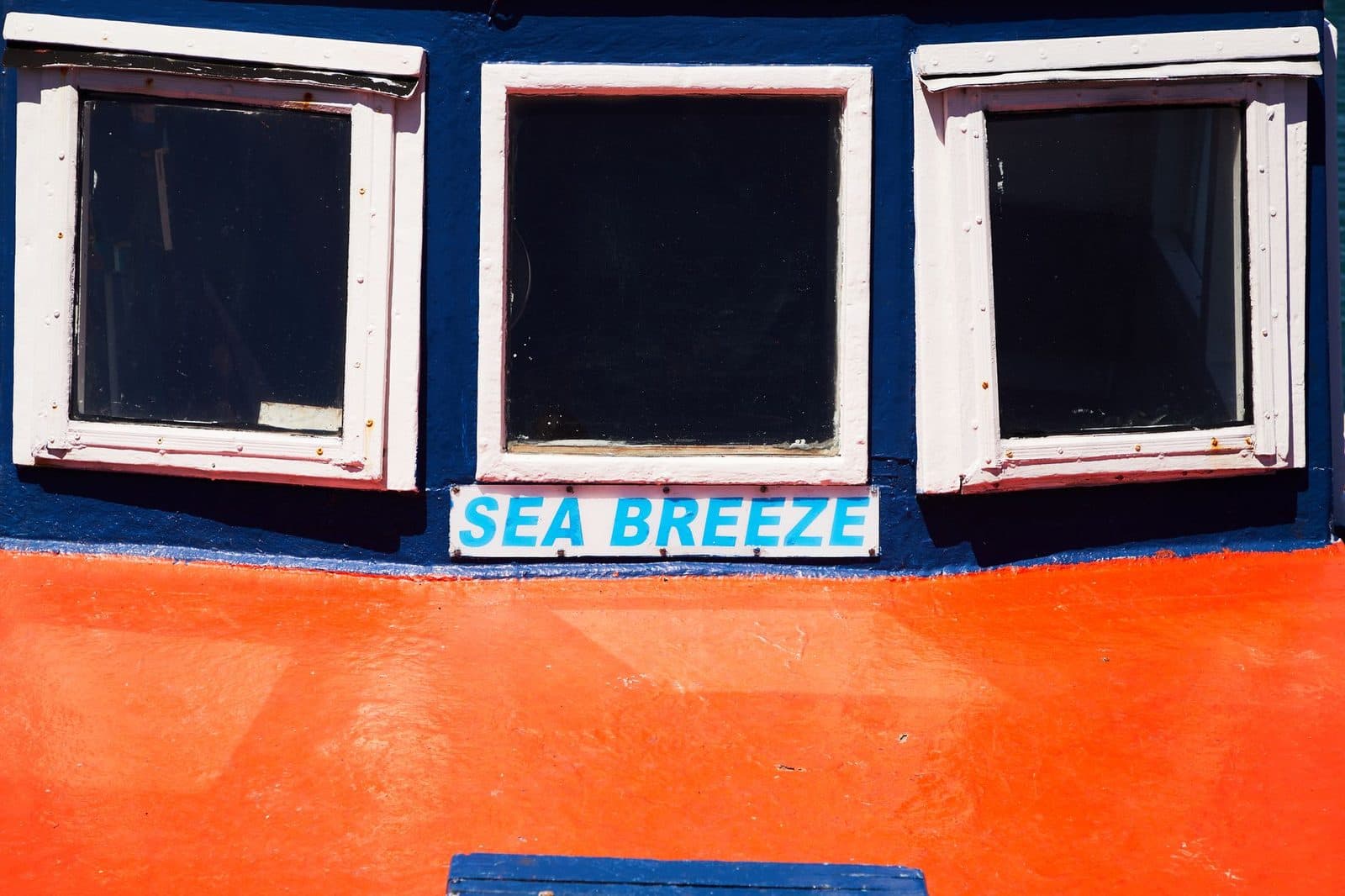 Motor ship with square shaped windows painted in red and blue colors and inscription sea breeze