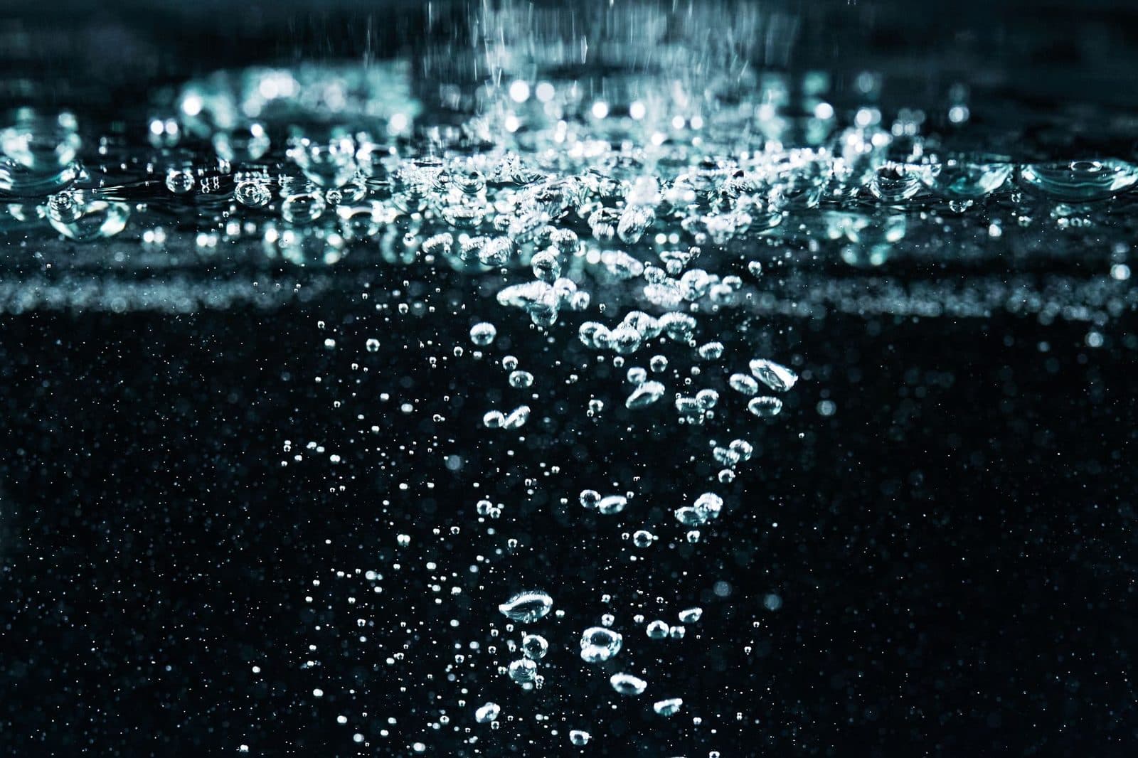 A detailed macro shot of effervescent bubbles rising in water, showcasing fizz and movement.