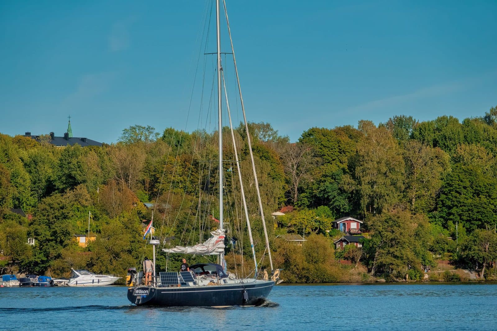 Sailboat on calm waters surrounded by lush greenery in Stockholm, Sweden.