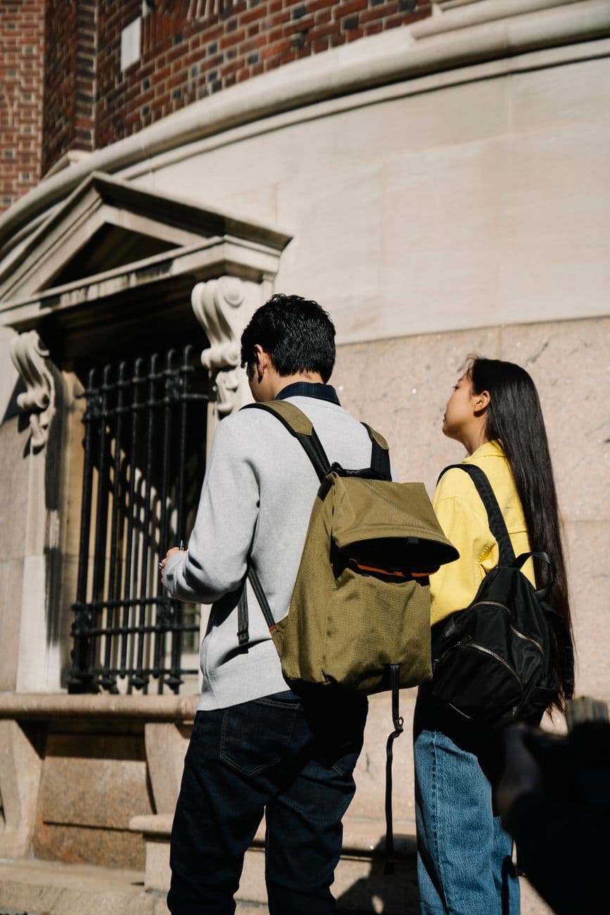 Two young adults with backpacks exploring historic urban architecture.