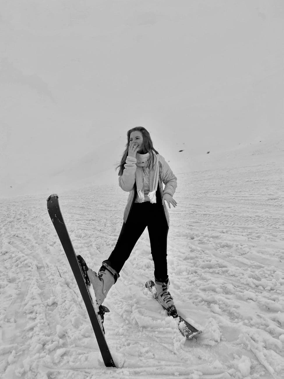 A woman skier in winter gear standing on a snow-covered slope, enjoying the weather.