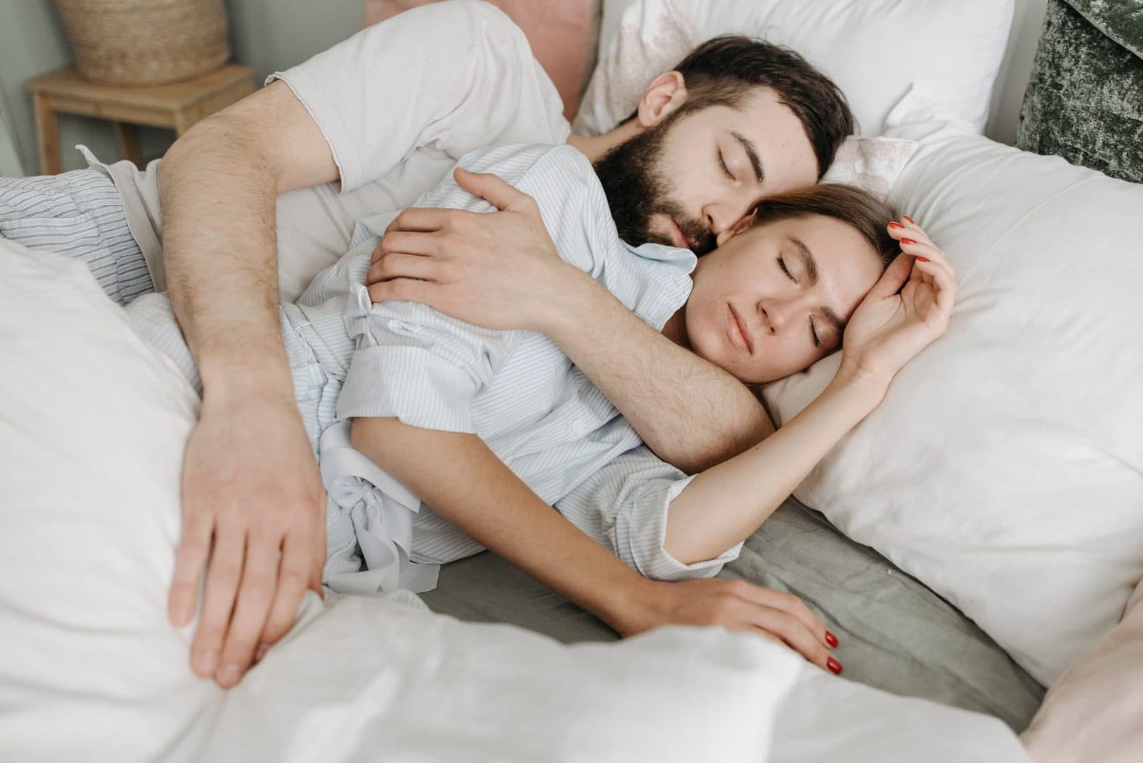 A loving couple embraces warmly in a cozy bedroom setting.