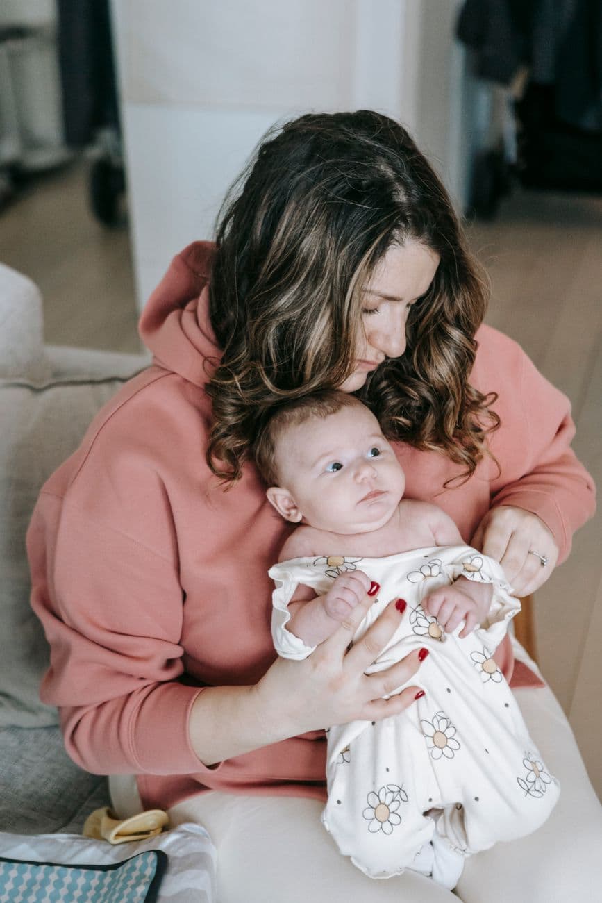 Tender moment of a mother holding her baby indoors, showcasing warmth and bonding.