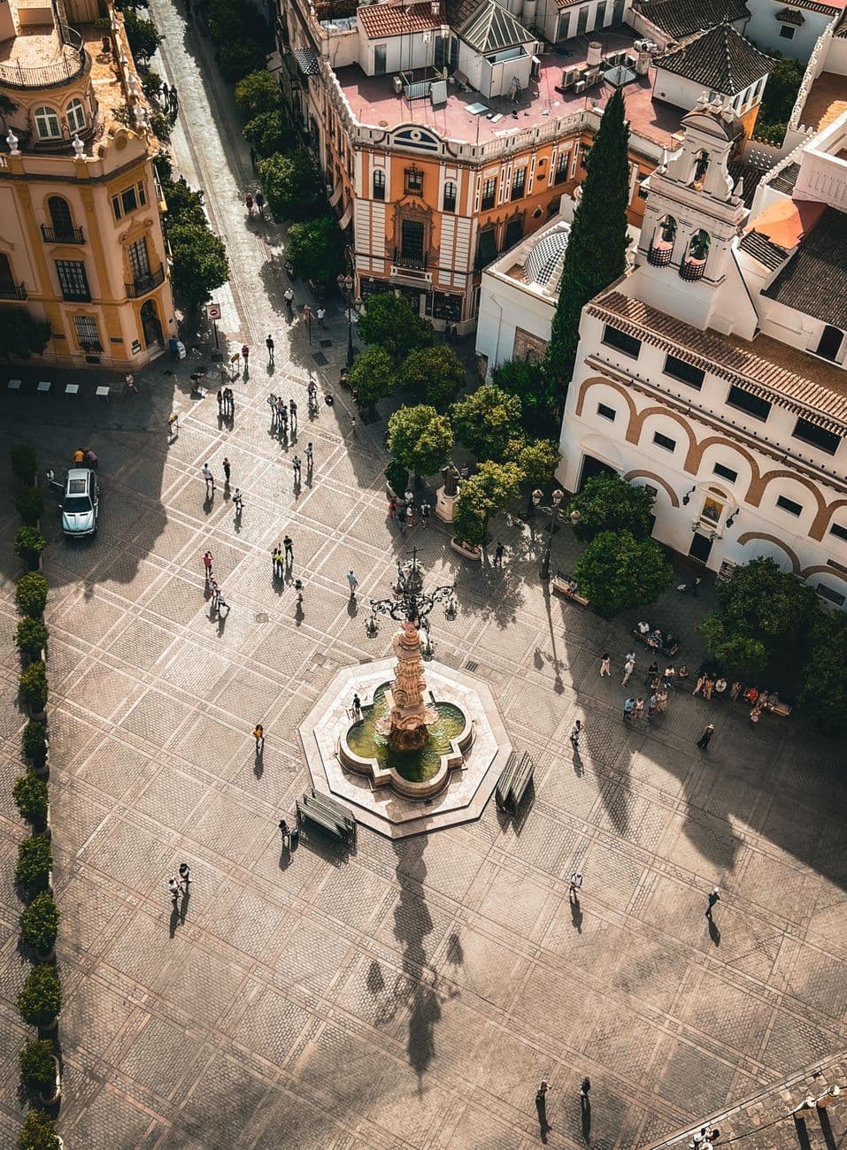 Aerial view of a bustling historic plaza in Seville, showcasing beautiful architecture and lively street life.