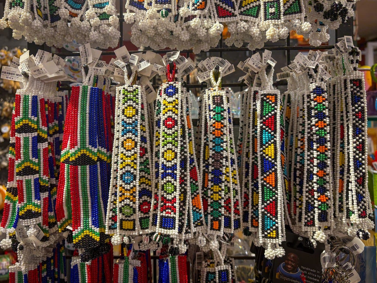 Colorful African beaded crafts hanging in a souvenir shop, showcasing traditional artistry.