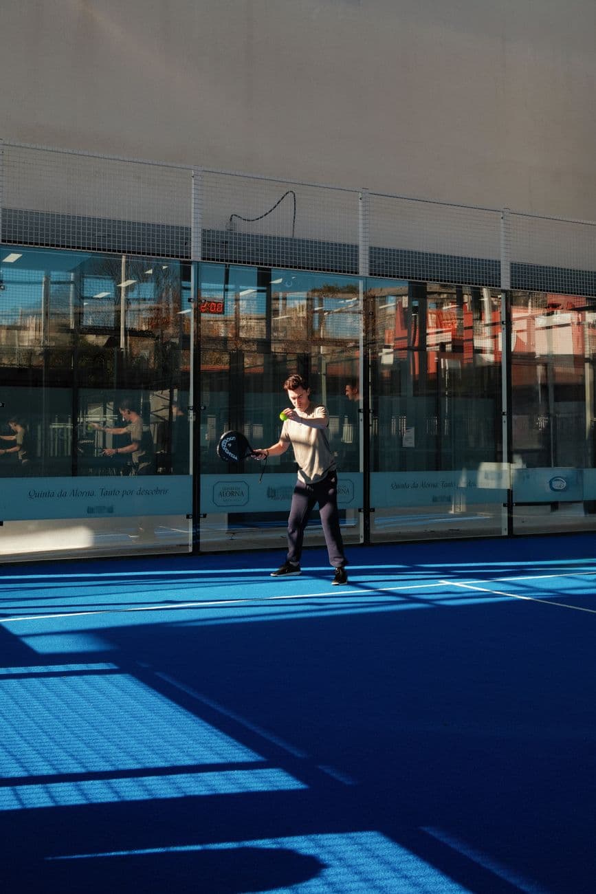 Adult playing paddle tennis on a striking blue court in Lisbon, Portugal.