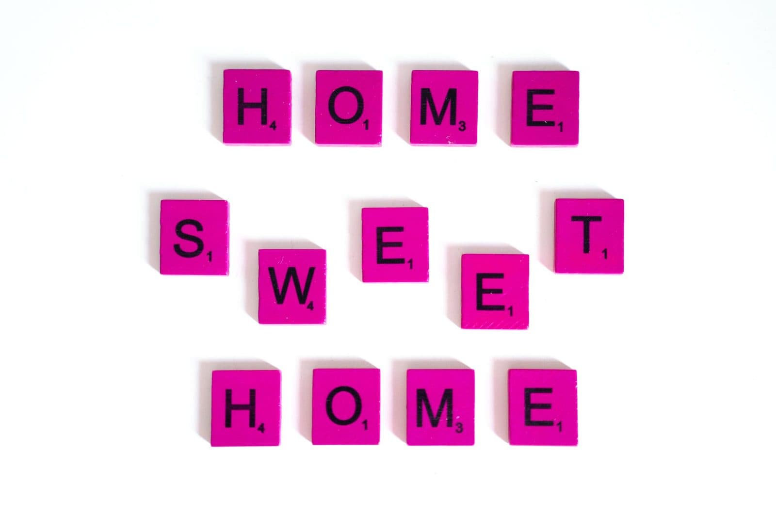 Pink Scrabble tiles spelling 'Home Sweet Home' on a white background for cozy decor.