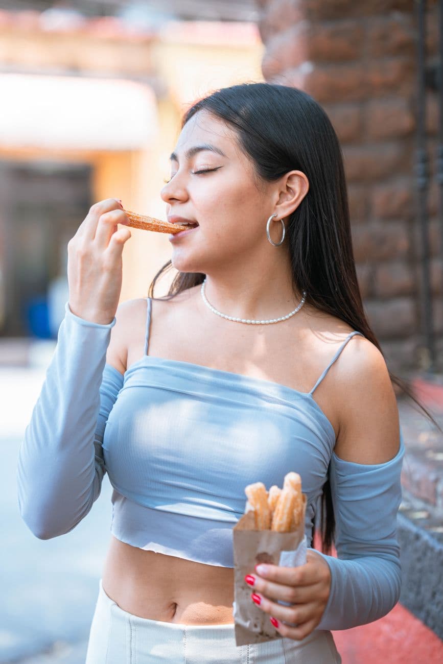 A young woman savors churros outdoors in vibrant Ciudad de México.