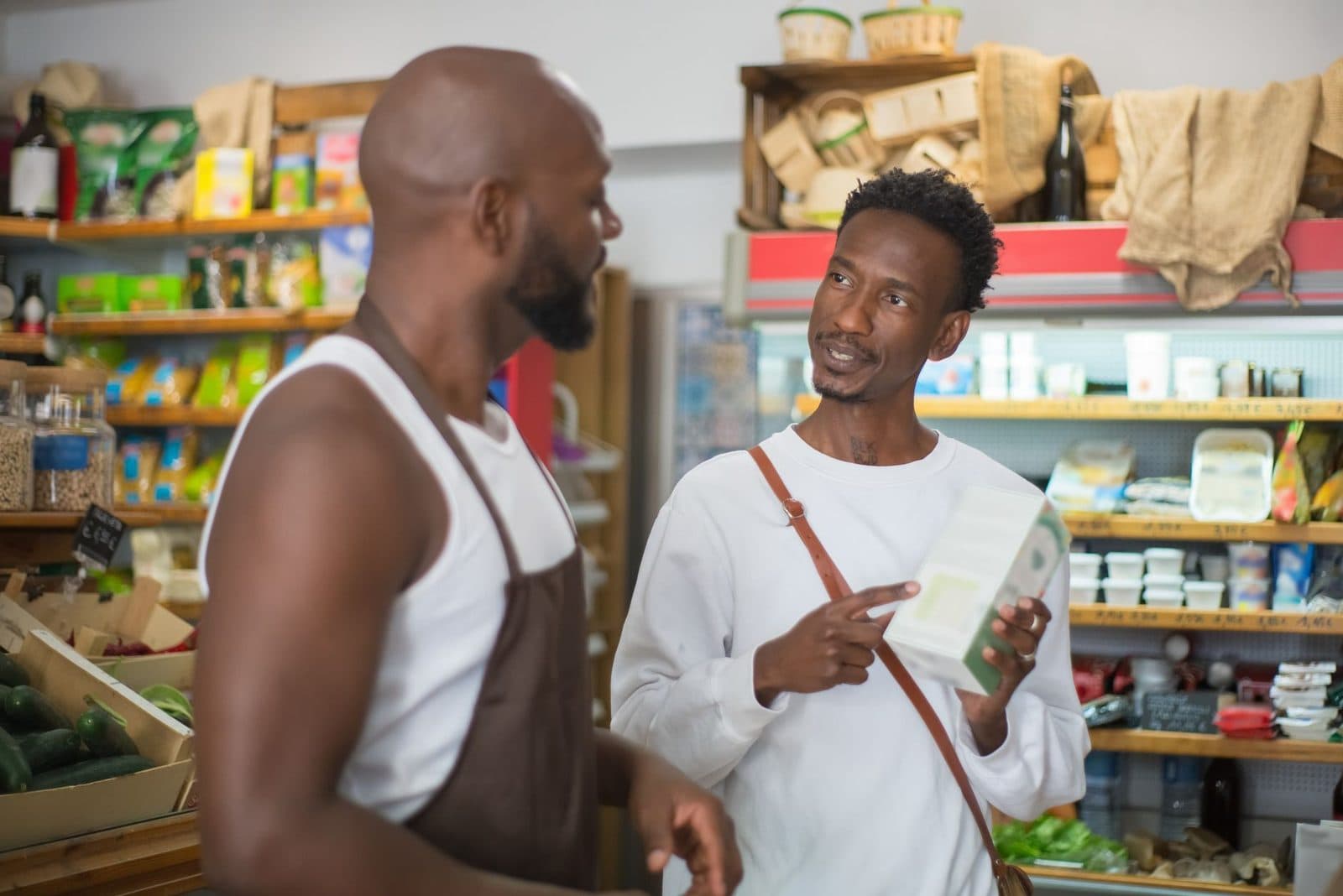 Customer and seller in a lively discussion at a grocery store, exchanging views over products.