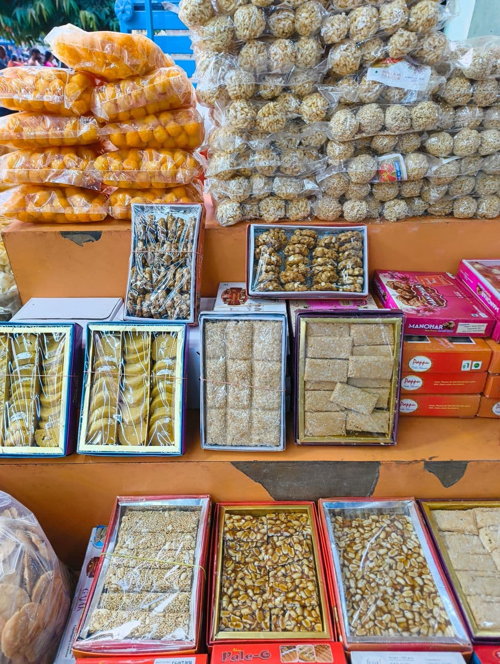 Colorful display of traditional Indian sweets and snacks at a local market.