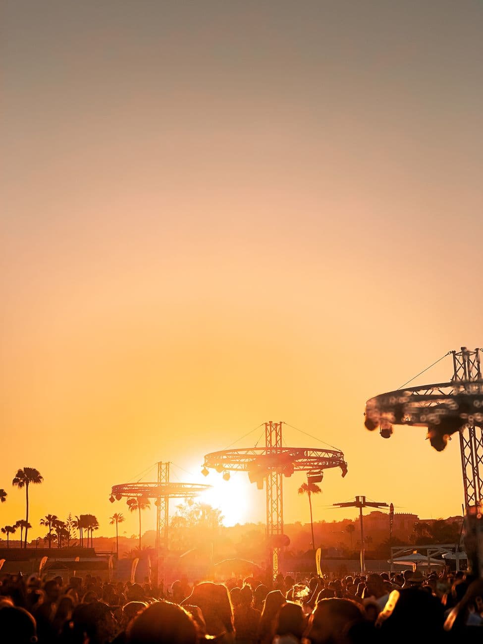 Vibrant sunset over a festival in Maspalomas, Canary Islands, capturing palm trees and party goers.
