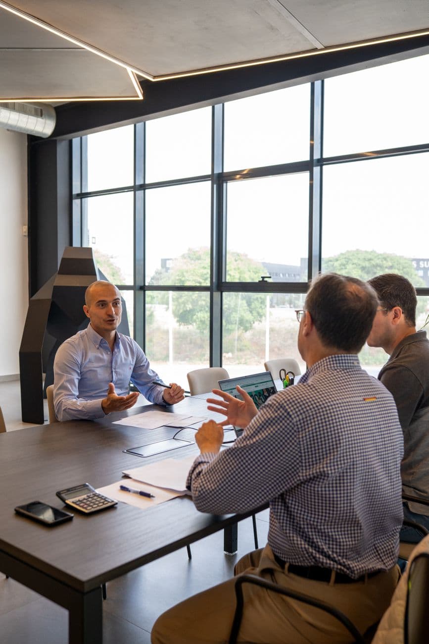 Three professionals in a productive meeting at a Valencia office, discussing strategy and collaboration.