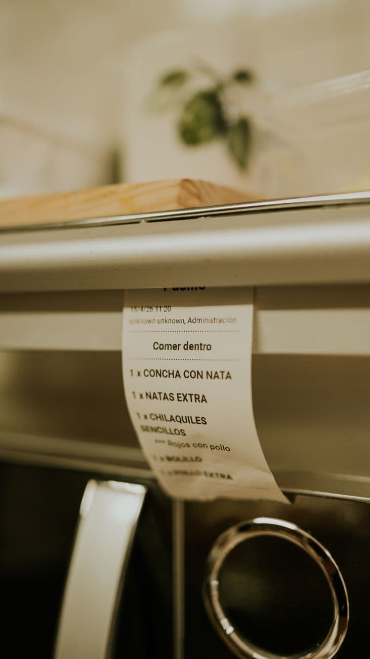Close-up of a restaurant kitchen order ticket listing various food items in a warm, muted setting.
