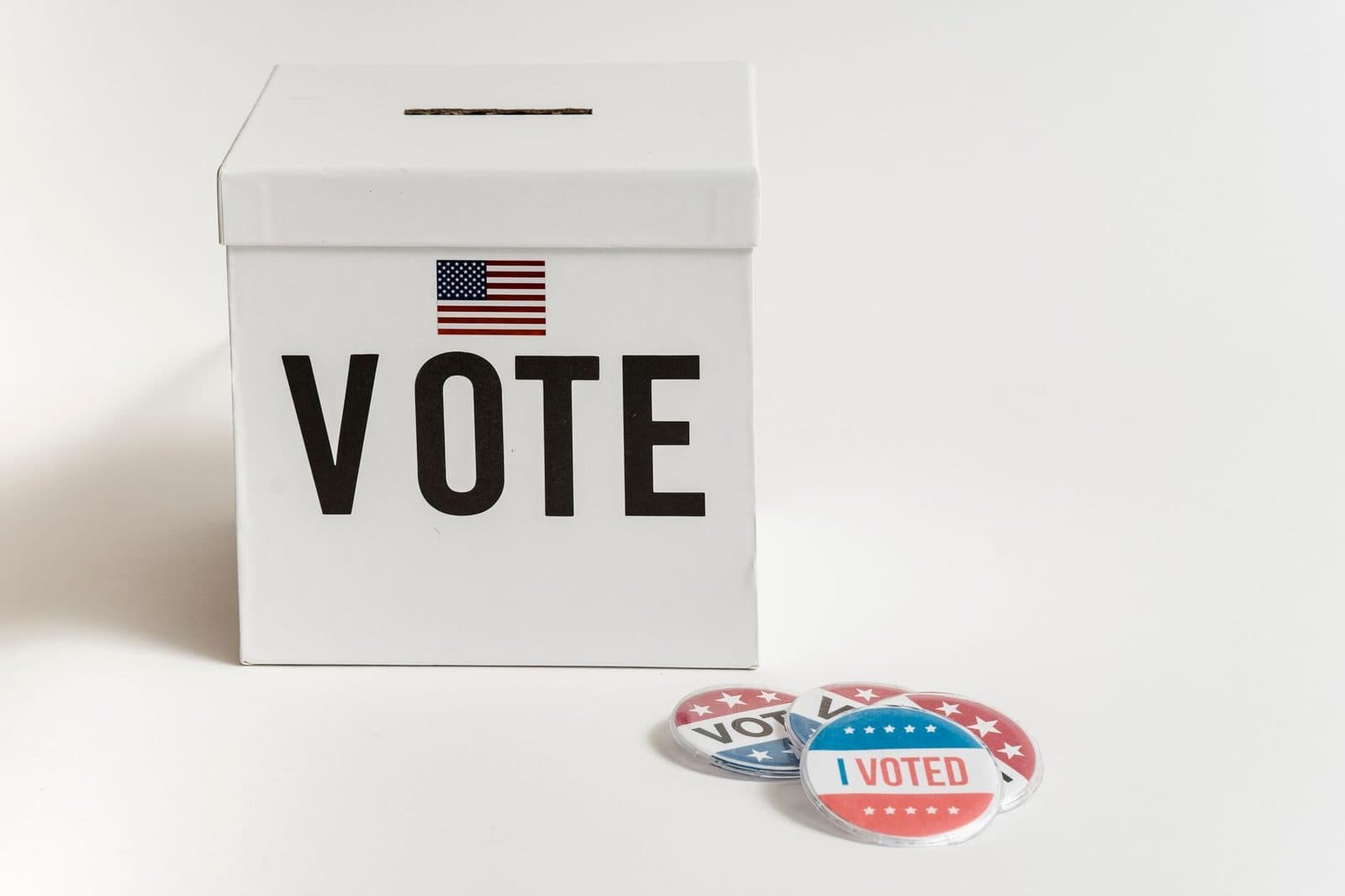 White ballot box with USA flag and 'I Voted' badges on a white background.