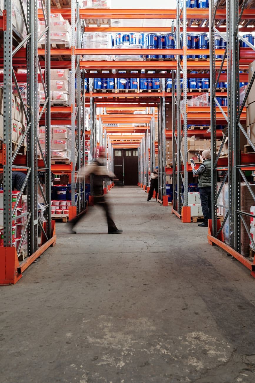 Industrial warehouse with shelves and a moving worker, showcasing organized storage.