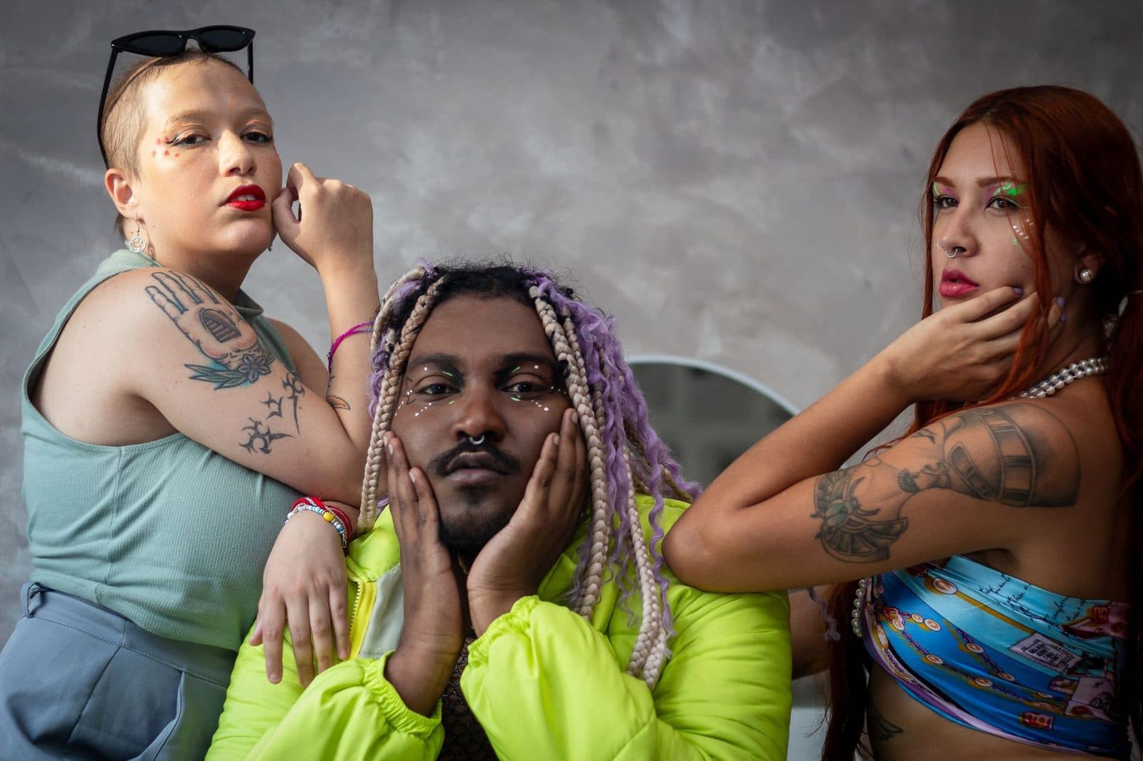 A stylish group of individuals showcasing tattoos and vibrant hairstyles indoors.