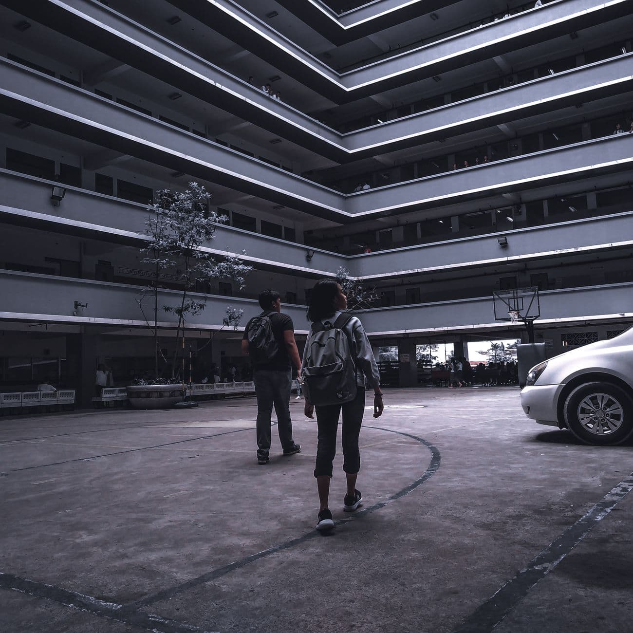 Two backpackers walk through a modern courtyard, highlighting university life in Cebu City.
