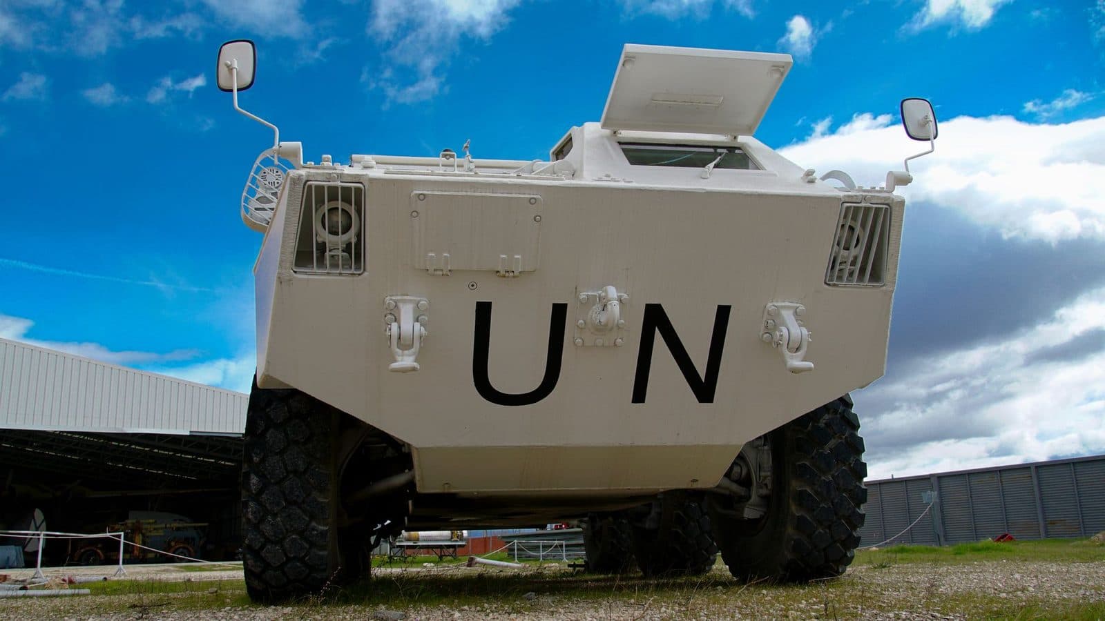 Low-angle view of a UN armored vehicle in Madrid, with clear blue sky and industrial background.