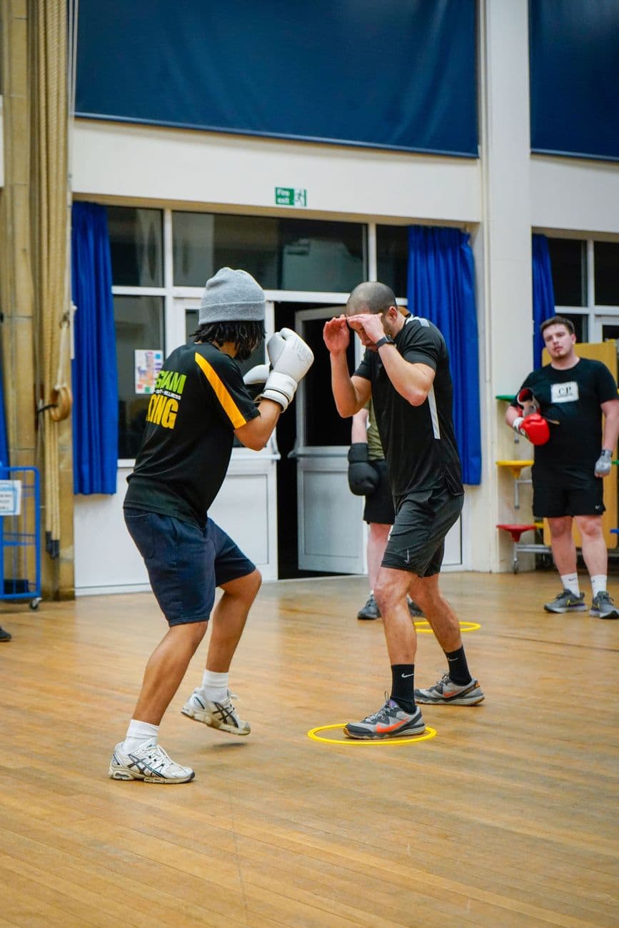 Amateur boxers practice jabs and defenses during an indoor training session.