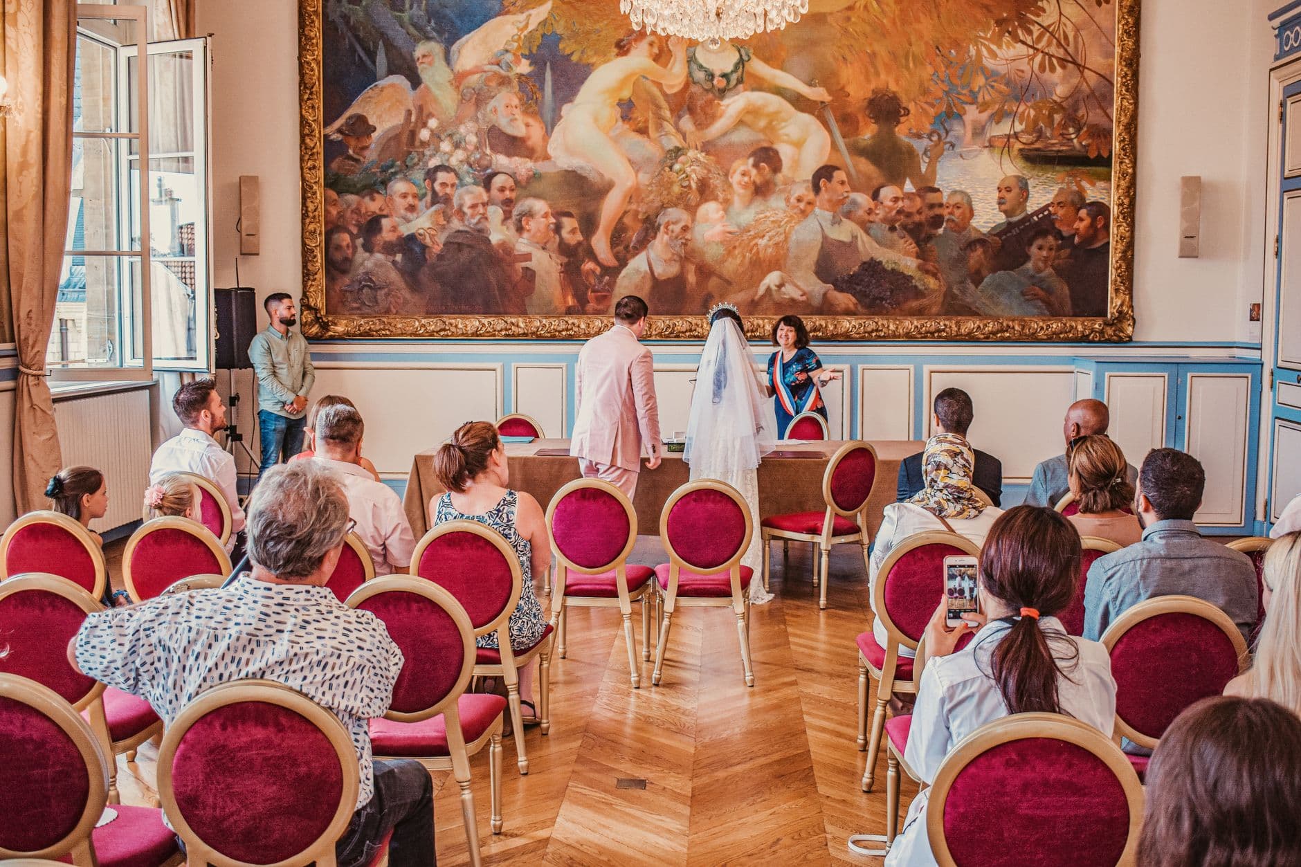 A beautiful wedding ceremony inside a Paris city hall, featuring a bride in a veil and groom with guests.