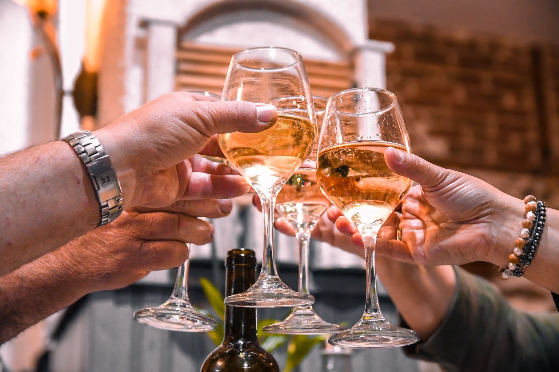 Close-up of friends toasting with white wine glasses in an indoor setting.