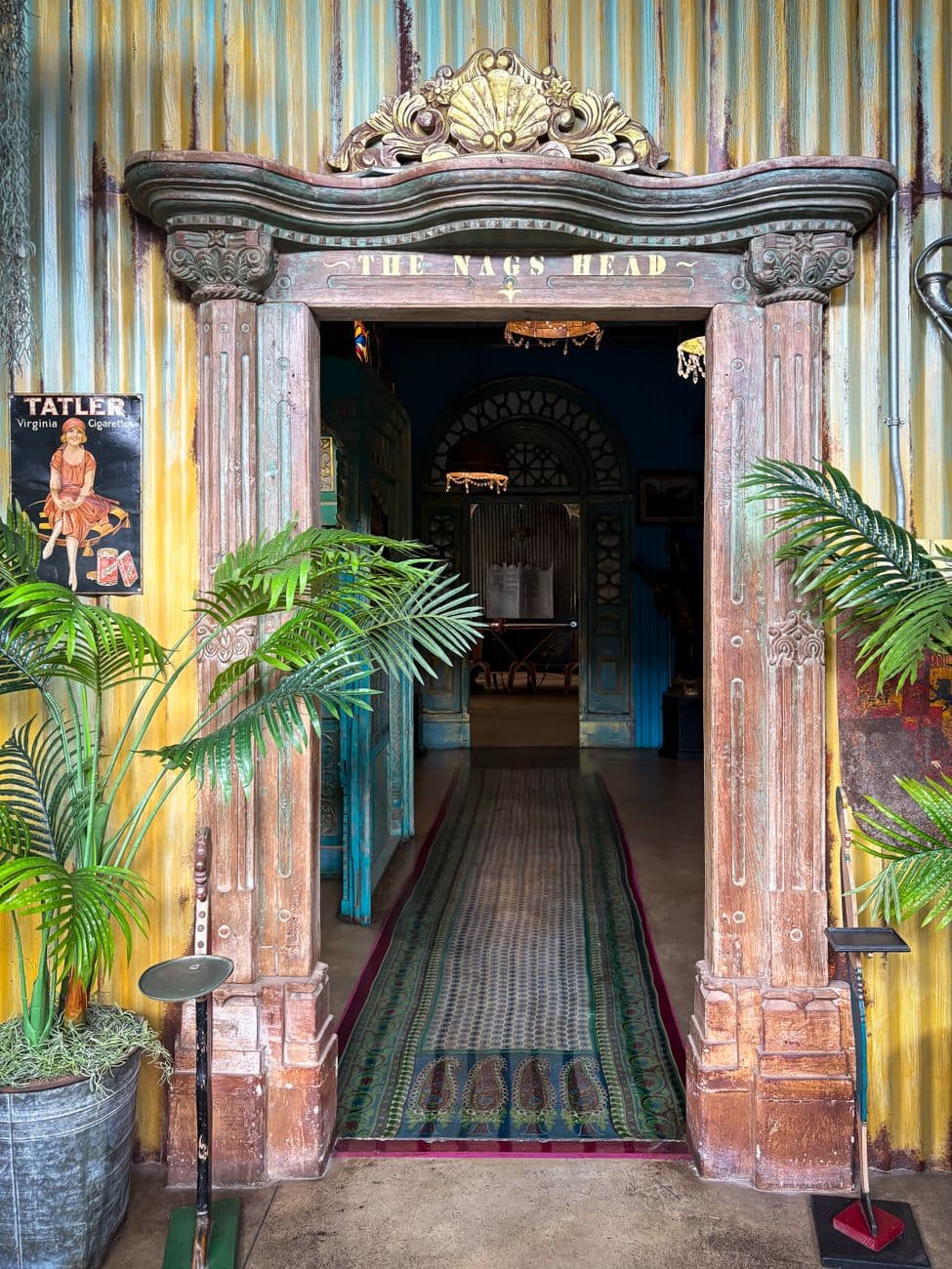 Richly textured entrance to The Nag's Head with vintage decor and lush plants.