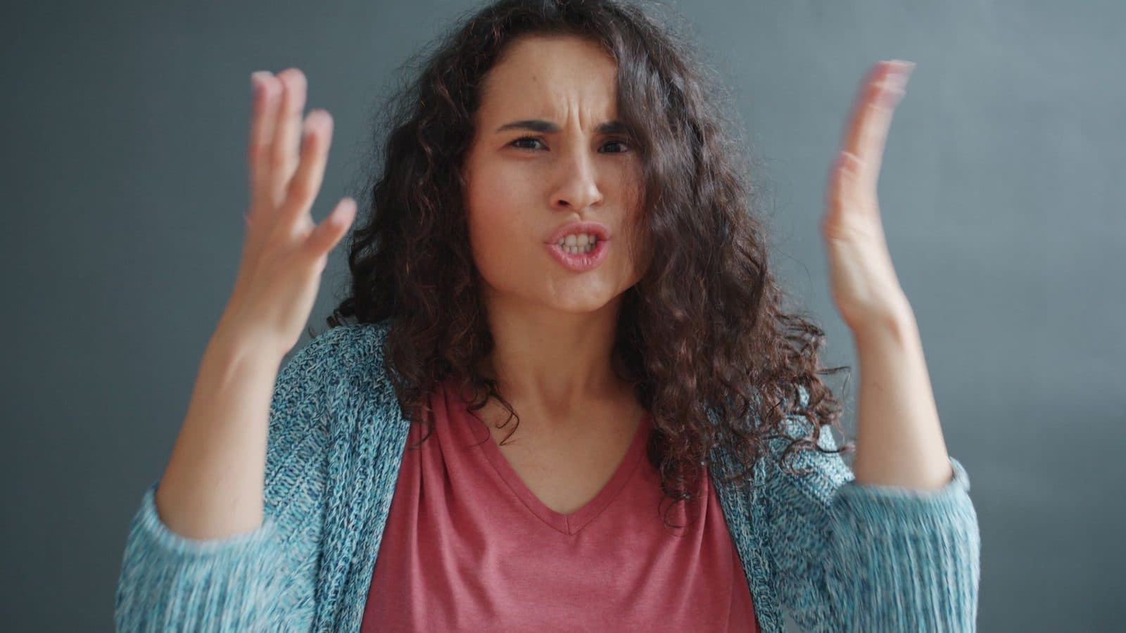 Young woman expressing emotions with animated gestures indoors.
